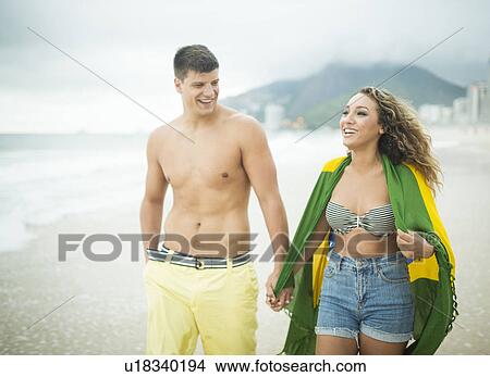 Picture - Young couple strolling, woman wrapped in brazilian flag, Ipanema Beach, Rio de Janeiro, Brazil. Fotosearch