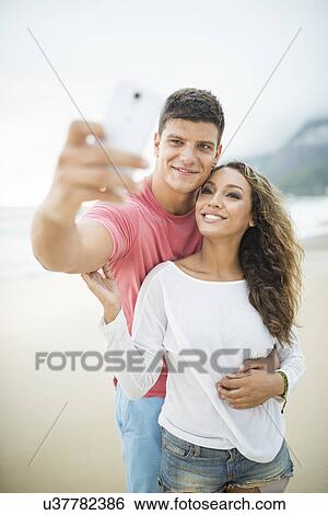 Young couple taking self portrait on Ipanema Beach, Rio de Janeiro, Brazil View Large Photo Image Stock Photograph - Young couple taking self portrait on Ipanema Beach, Rio de Janeiro, Brazil. Fotosearch