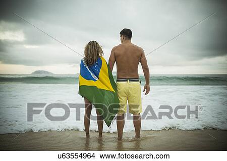 Picture - Young couple, woman wrapped in brazilian flag, Ipanema Beach, Rio de Janeiro, Brazil. Fotosearch
