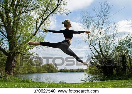 Young female dancer jumping mid air near lake View Large Photo Image Stock Image - Young female dancer jumping mid air near lake. Fotosearch