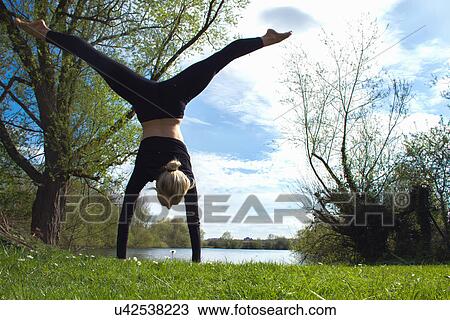 Young female dancer poised in handstand near lake View Large Photo Image Stock Image - Young female dancer poised in handstand near lake. Fotosearch