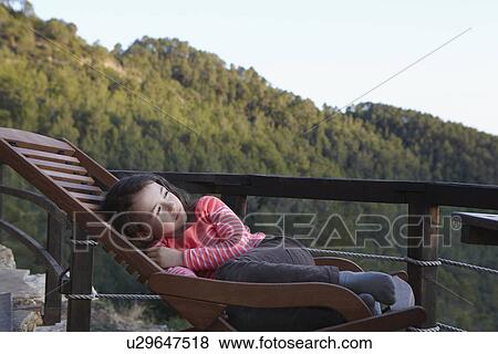 Young girl curled up on balcony deckchair gazing upward View Large Photo Image Stock Photo - Young girl curled up on balcony deckchair gazing upward. Fotosearch