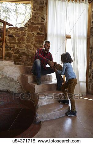 Young girl handing log to her father on sitting room stairs View Large Photo Image Stock Photography - Young girl handing log to her father on sitting room stairs. Fotosearch
