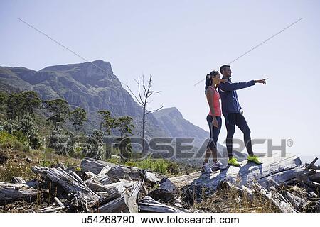 Stock Image - Young joggers enjoying view from hilltop. Fotosearch