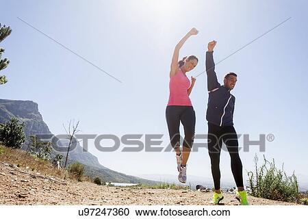 Young joggers jumping in mid air View Large Photo Image Stock Image - Young joggers jumping in mid air. Fotosearch