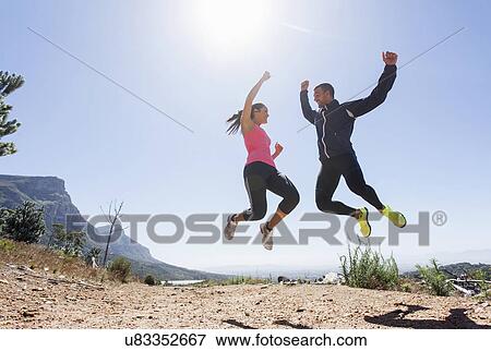 Young joggers jumping in mid air View Large Photo Image Stock Photo - Young joggers jumping in mid air. Fotosearch