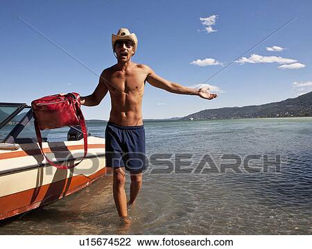 Stock Image - Young man carrying bag from power boat, Verbania, Italy. Fotosearch