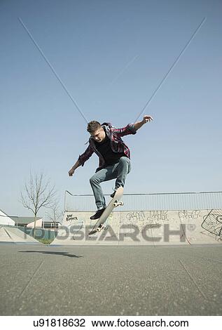 Stock Image - Young man doing skateboarding trick. Fotosearch