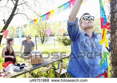 Young man hanging up bunting View Large Photo Image Stock Photo - Young man hanging up bunting. Fotosearch