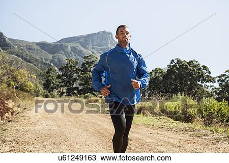 Stock Image - Young man jogging in forest. Fotosearch