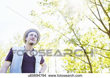 Picture - Young man wearing straw hat, low angle. Fotosearch