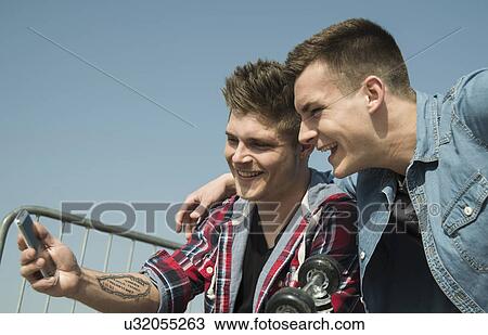 Young men in skatepark, taking self portrait photograph, using smartphone View Large Photo Image Stock Image - Young men in skatepark, taking self portrait photograph, using smartphone. Fotosearch