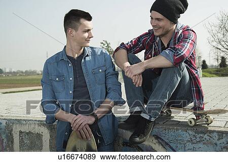 Stock Photo - Young men sitting together at skatepark. Fotosearch