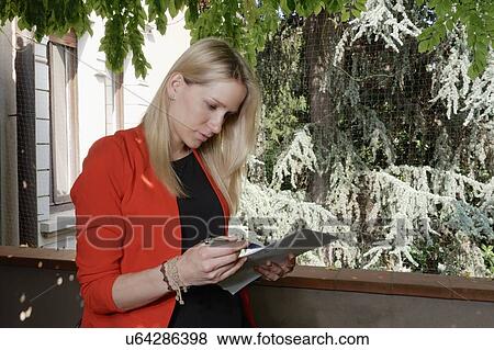 Young woman checking paperwork on balcony View Large Photo Image Stock Photo - Young woman checking paperwork on balcony. Fotosearch