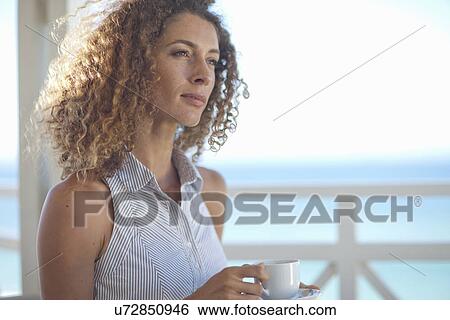 Young woman gazing out to sea from beach house balcony View Large Photo Image Stock Photograph - Young woman gazing out to sea from beach house balcony. Fotosearch