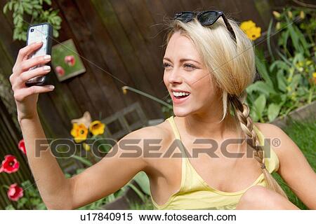 Young woman in garden taking selfie on smartphone View Large Photo Image Stock Photography - Young woman in garden taking selfie on smartphone. Fotosearch