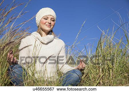 Young woman in yoga lotus position in long grass View Large Photo Image Stock Photo - Young woman in yoga lotus position in long grass. Fotosearch