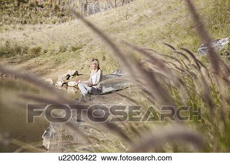 Young woman in yoga position at lakeside View Large Photo Image Stock Image - Young woman in yoga position at lakeside. Fotosearch