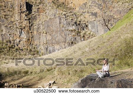 Young woman in yoga position on lakeside rock View Large Photo Image Stock Image - Young woman in yoga position on lakeside rock. Fotosearch