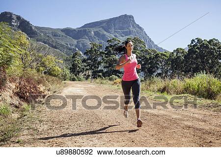 Stock Image - Young woman jogging in forest. Fotosearch
