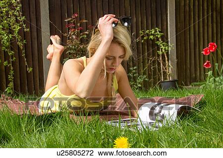 Young woman lying in garden reading magazine View Large Photo Image Stock Image - Young woman lying in garden reading magazine. Fotosearch