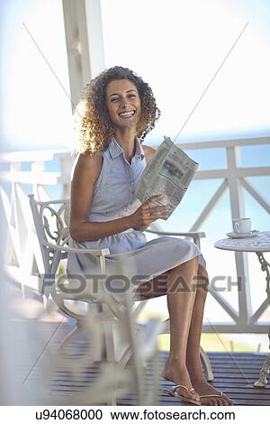 Young woman reading newspaper on beach house balcony View Large Photo Image Stock Image - Young woman reading newspaper on beach house balcony. Fotosearch