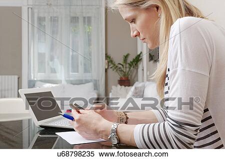 Young woman reading text message on smartphone at home desk View Large Photo Image Stock Photography - Young woman reading text message on smartphone at home desk. Fotosearch