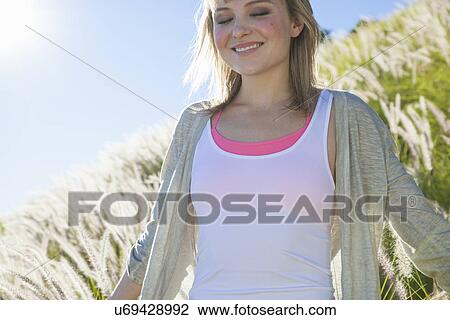 Young woman smiling with eyes closed in long grass View Large Photo Image Stock Image - Young woman smiling with eyes closed in long grass. Fotosearch