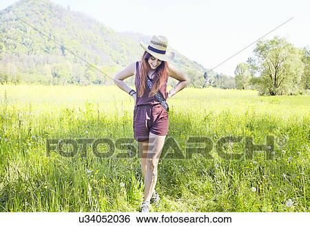 Young woman standing in field View Large Photo Image Stock Photograph - Young woman standing in field. Fotosearch