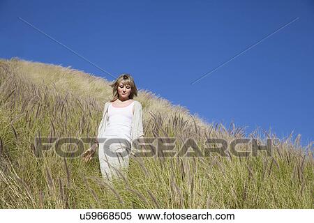 Young woman strolling through long grass View Large Photo Image Stock Photography - Young woman strolling through long grass. Fotosearch