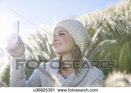 Young woman taking selfie on smartphone in long grass View Large Photo Image Stock Image - Young woman taking selfie on smartphone in long grass. Fotosearch