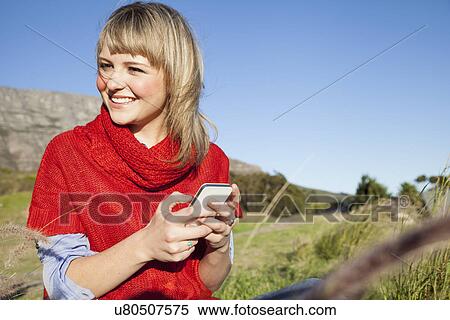 Young woman texting on smartphone in field View Large Photo Image Stock Photography - Young woman texting on smartphone in field. Fotosearch