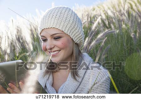 Stock Photo - Young woman with digital tablet in long grass. Fotosearch