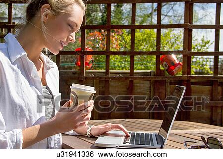 Young woman with takeaway coffee and laptop in garden View Large Photo Image Stock Photograph - Young woman with takeaway coffee and laptop in garden. Fotosearch
