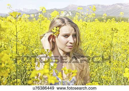 Stock Photo - Young woman with yellow flower in hair, portrait. Fotosearch