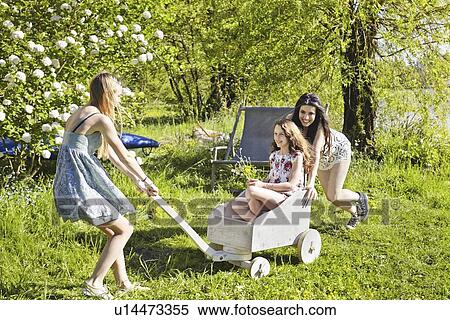 Stock Photography - Young women playing with toy cart. Fotosearch