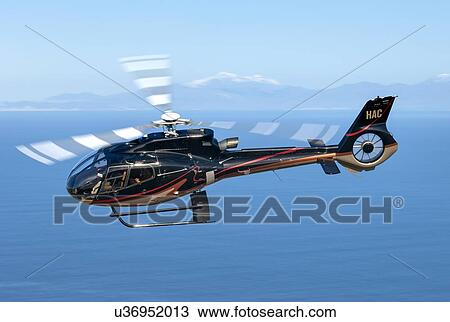 Stock Image - Eurocopter EC130B4 in flight off the west coast of Wellington. Fotosearch