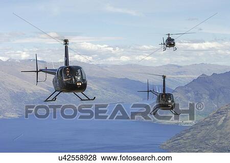 Stock Photo - Helicopter formation over Lake Wakatipu near Queenstown, New Zealand; two Robinson R44s and a Eurocopter AS350. Fotosearch