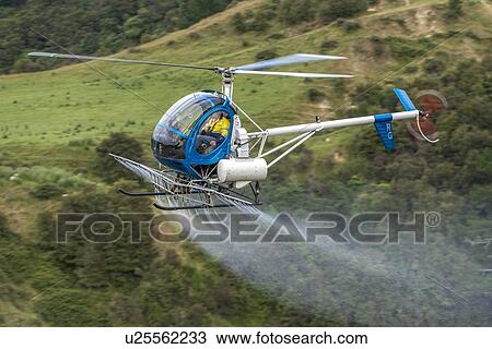 Stock Image - Hughes 269C flight conducting aerial spraying. Fotosearch