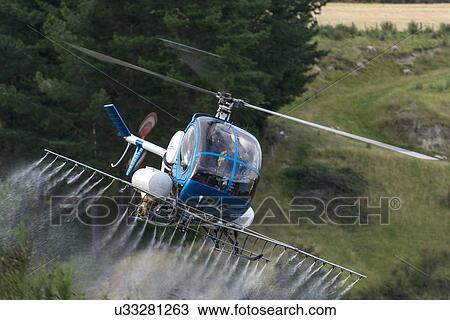 Stock Image - Hughes 269C in flight conducting aerial spraying. Fotosearch
