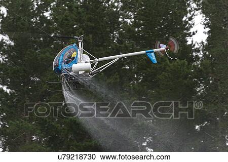 Stock Image - Hughes 269C in flight conducting aerial spraying. Fotosearch