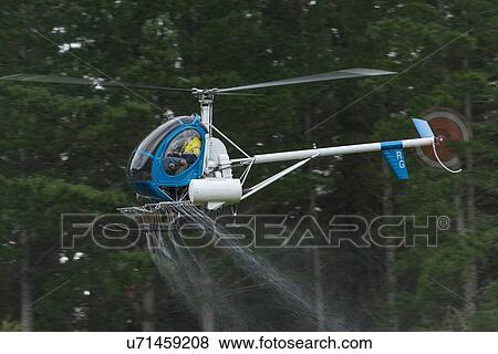 Stock Photo - Hughes 269C in flight conducting aerial spraying. Fotosearch