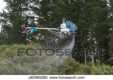 Stock Photography - Hughes 269C in flight conducting aerial spraying. Fotosearch