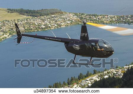 Picture - Robinson R44 helicopter in flight over Queenstown . Fotosearch