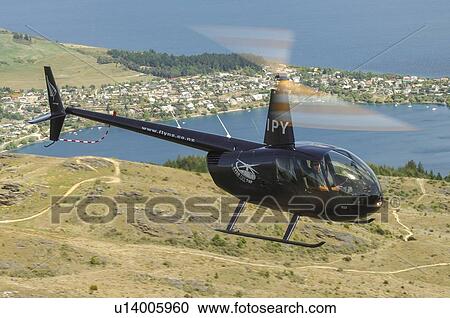 Stock Image - Robinson R44 helicopter in flight. Fotosearch