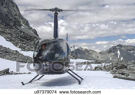 Picture - Robinson R44 helicopter landed on a mountain . Fotosearch