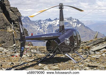 Stock Image - Robinson R44 helicopter landed on a mountain top near Queenstown. Fotosearch