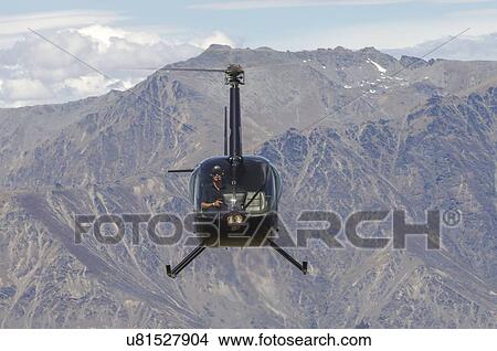 Picture - Robinspon R44 helicopter in flight over Queenstown and Lake Wakatipu, New Zealand. Fotosearch
