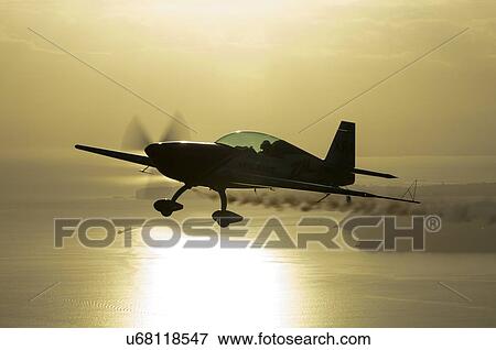 Stock Photo - Silhouette view of Extra Aircraft Extra 300 in flight over the Hauraki Gulf . Fotosearch