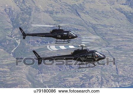 Stock Photograph - Two Eurocopter AS350 helicopters in formation over Queenstown, New Zealand. Fotosearch